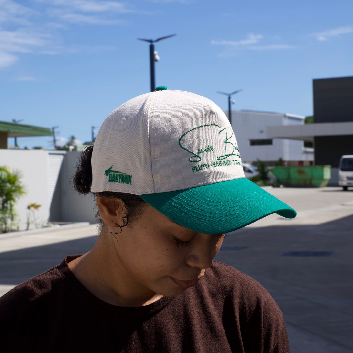 Person wearing a cap with a logo against a blue sky
