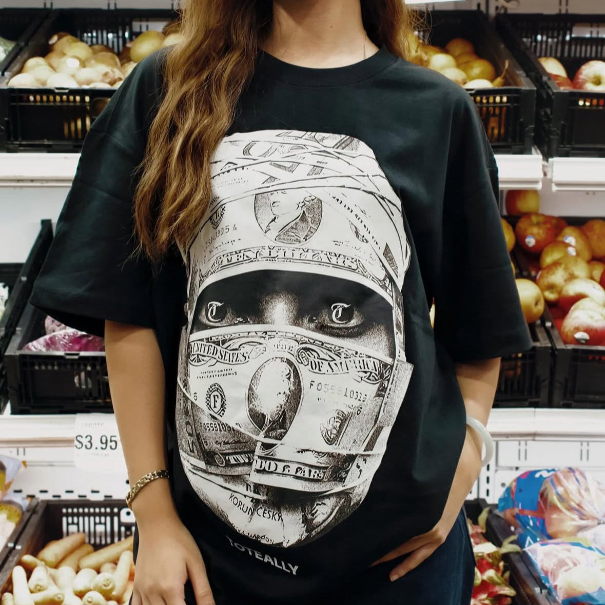 Person wearing a black t-shirt with a graphic design in a grocery store.
