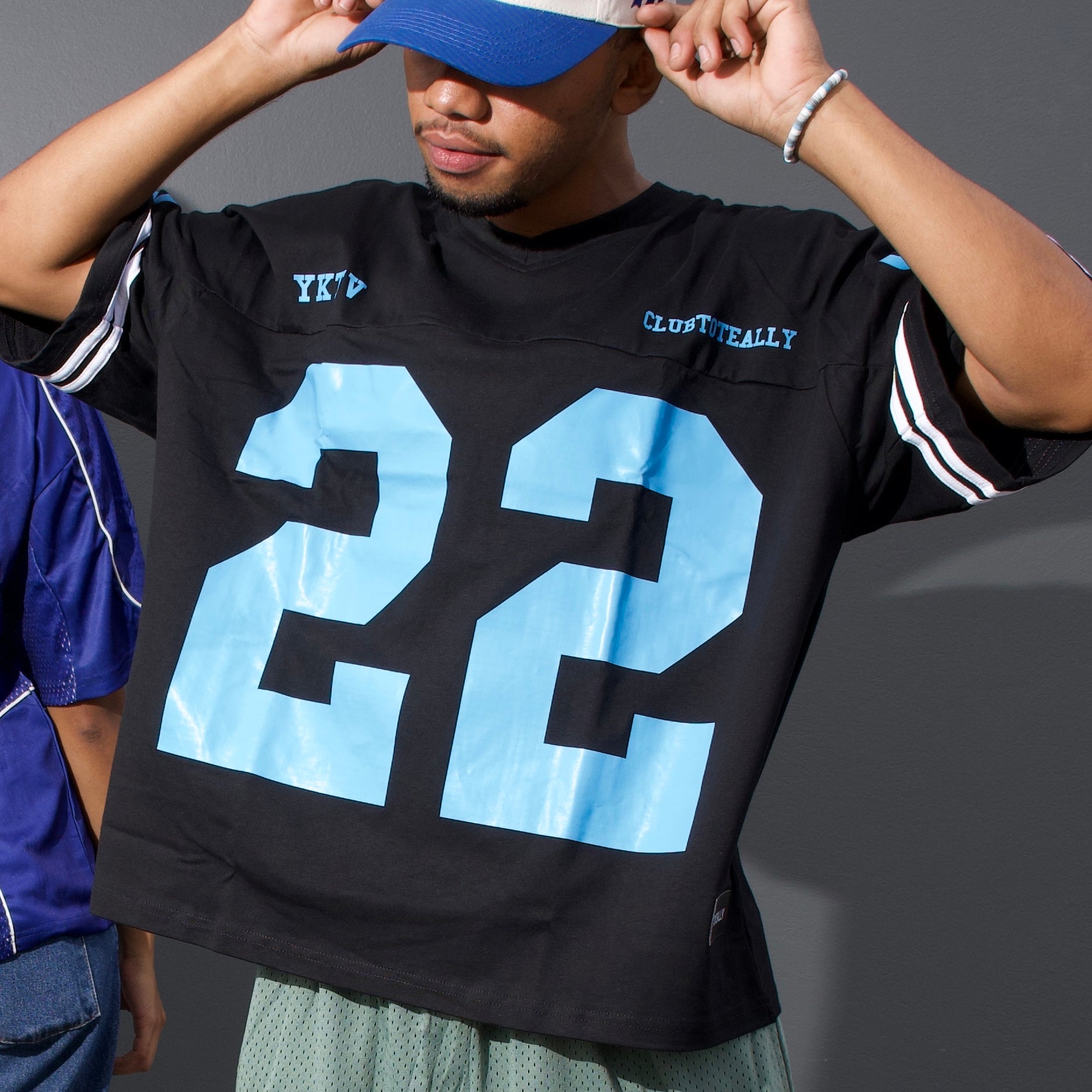 Person wearing a black sports jersey with blue numbers on a gray background