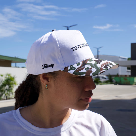 Person wearing a white cap and shirt with a logo, looking at a clear blue sky.