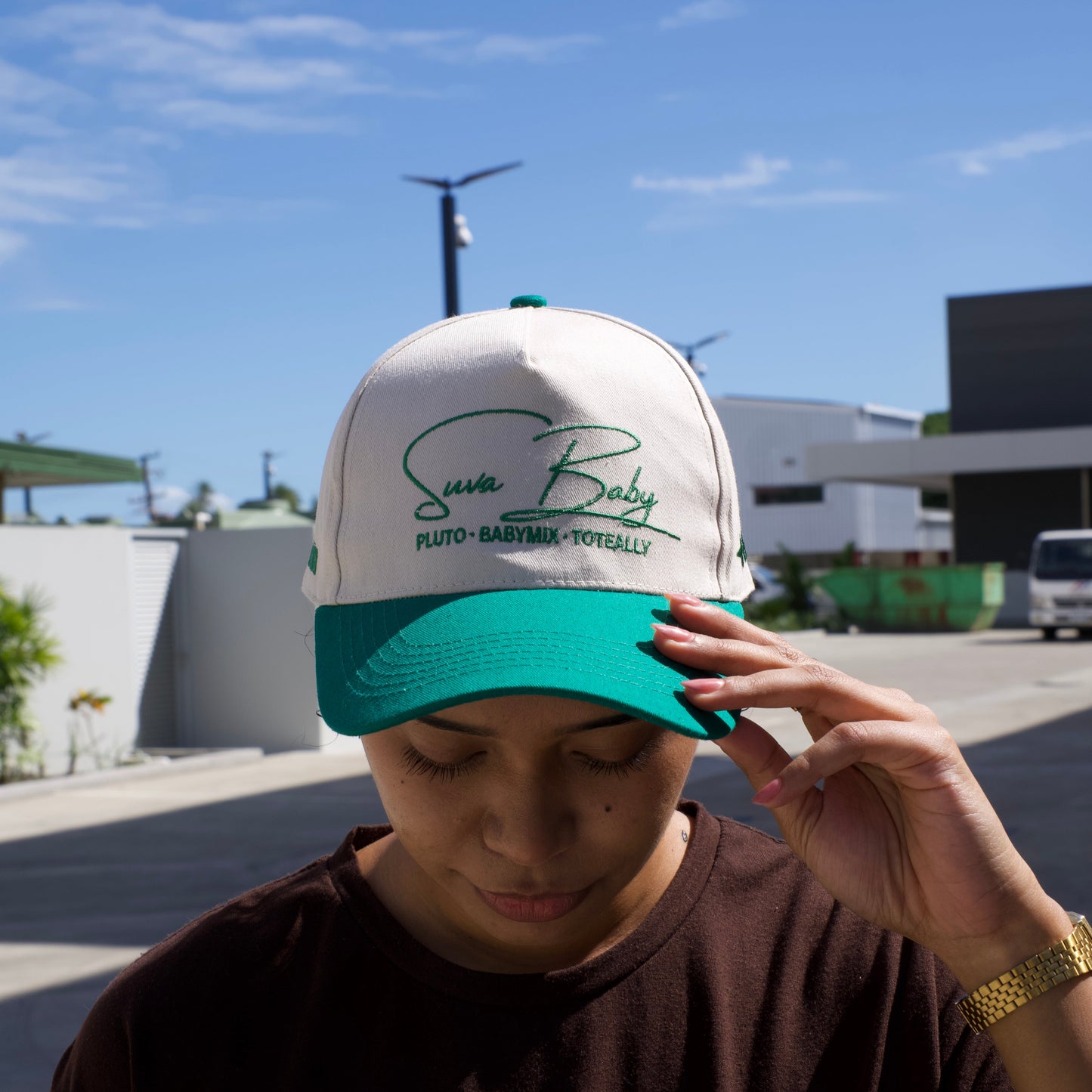 Person holding a cap with text against a blue sky
