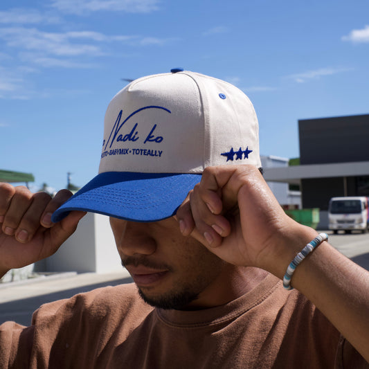 Person holding a white and blue cap against a clear blue sky