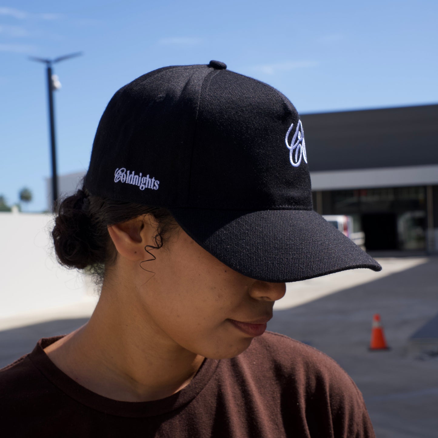 Person wearing a black cap with visible branding against a blue sky.