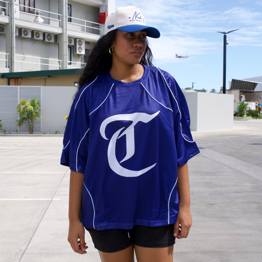 Person wearing a blue sports jersey with a logo on a tiled floor.