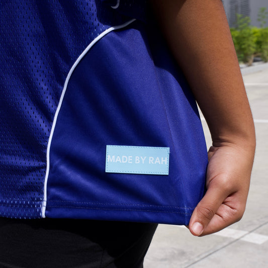 Close-up of a blue jacket with a brand label on a person sitting outdoors.