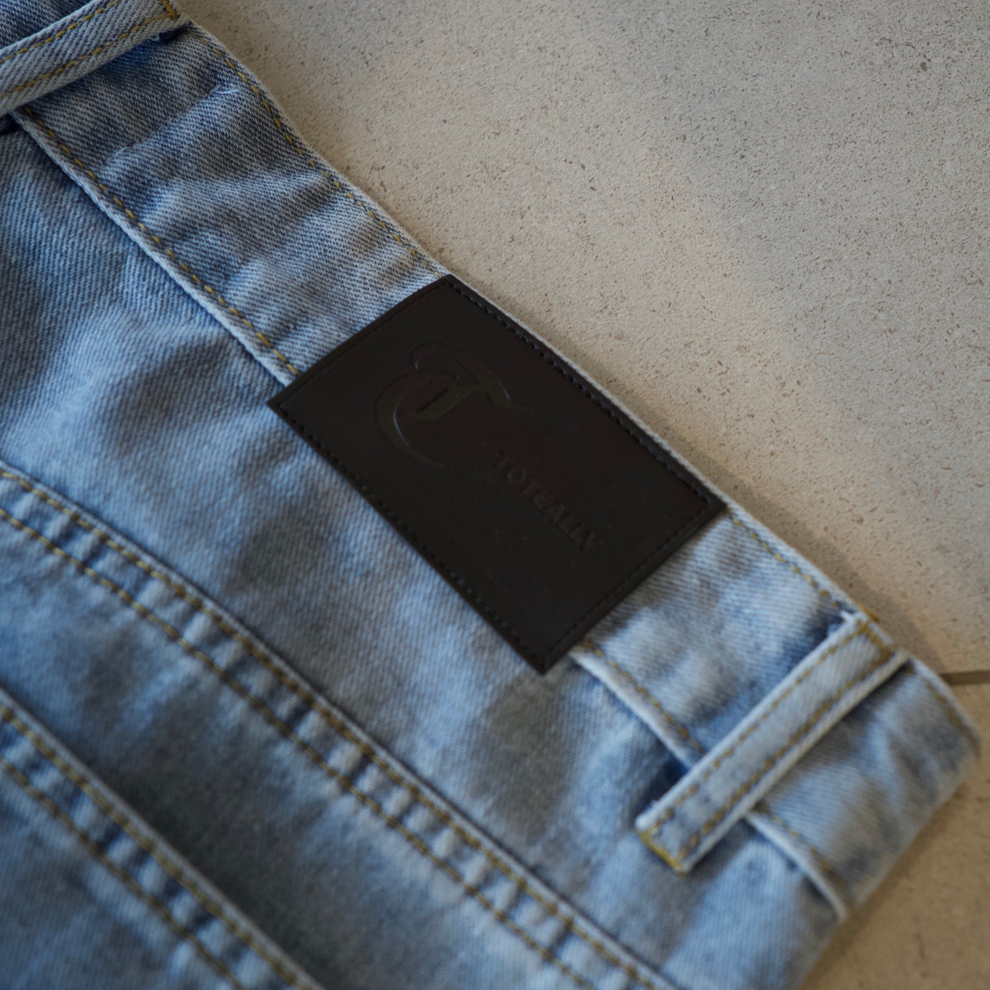 Close-up of a denim jacket with a brand label on a neutral background