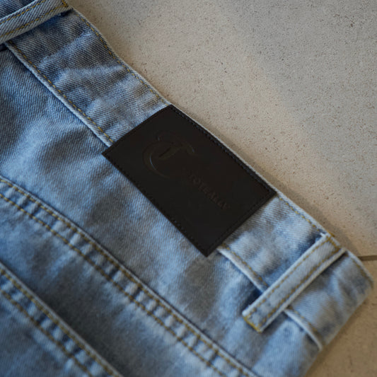 Close-up of a denim jacket with a brand label on a neutral background