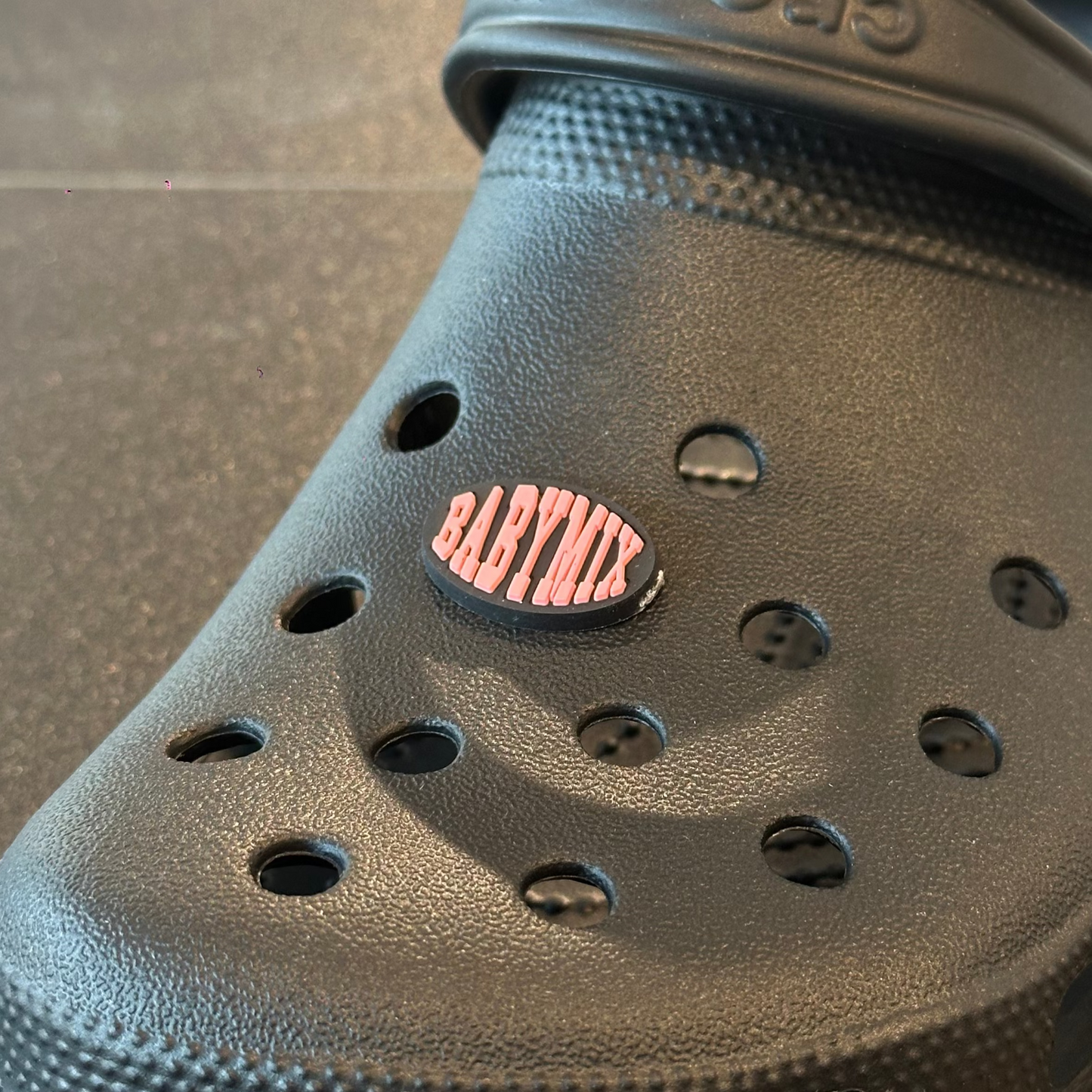 Black clog shoe with a visible brand logo on a dark surface