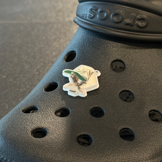 Black Crocs shoe with a small decorative item on a gray surface