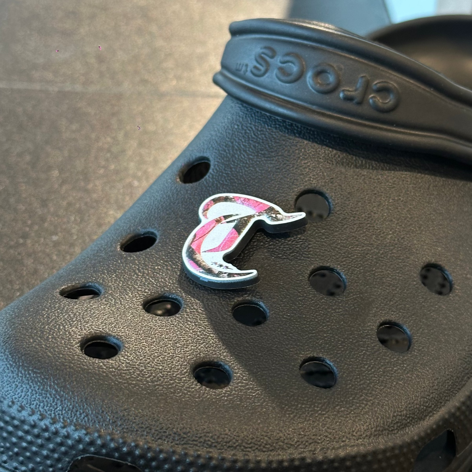 Black Crocs sandal with a logo on a gray surface