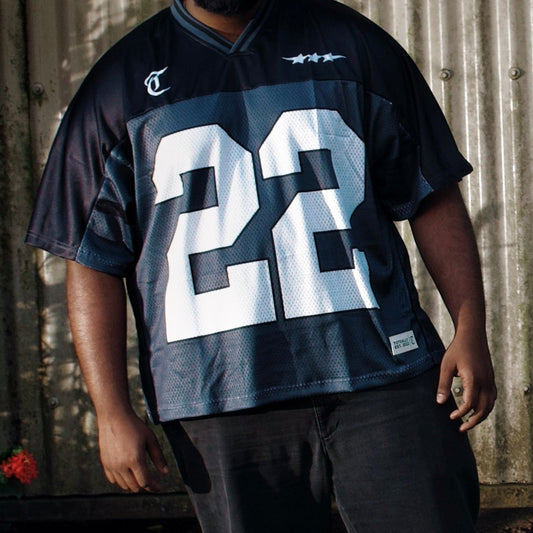 Person wearing a black sports jersey with the number 22 standing outdoors.